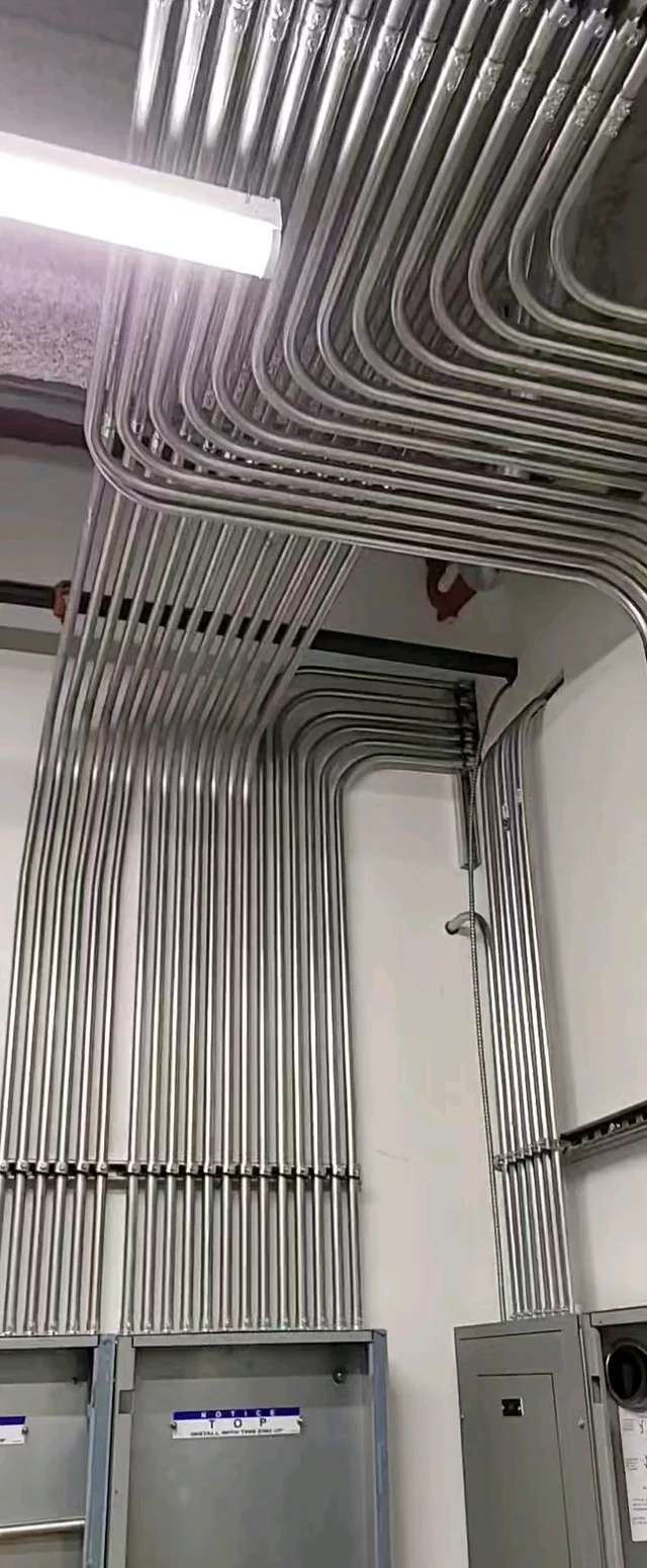 Neatly installed EMT conduit running along an industrial ceiling and wall